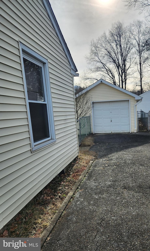 view of side of property with a detached garage, aphalt driveway, and an outbuilding