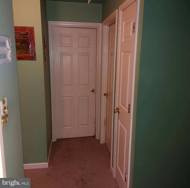 hallway with baseboards and light colored carpet