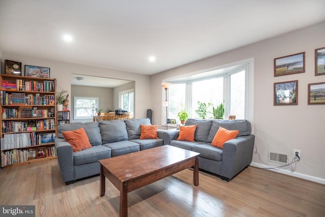 living area featuring light wood-type flooring, visible vents, and baseboards