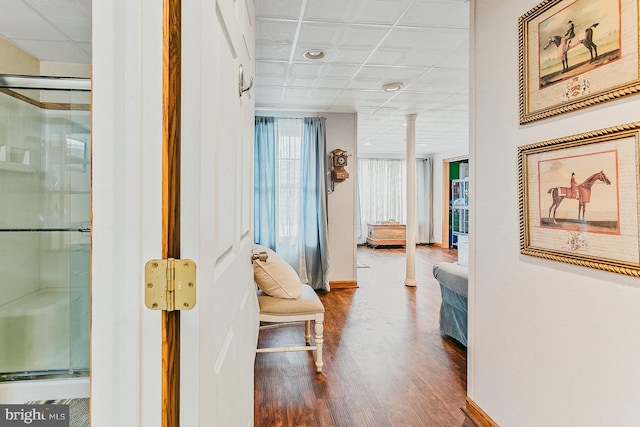 corridor featuring a drop ceiling and wood-type flooring