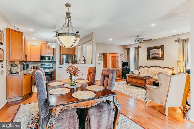 dining room with sink, ceiling fan, and light hardwood / wood-style flooring