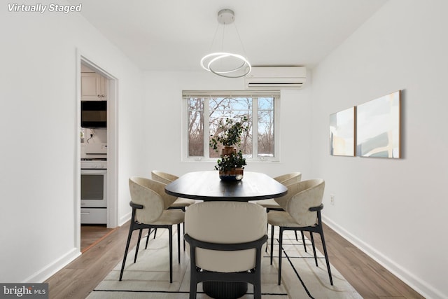 dining room featuring a wall unit AC, wood finished floors, and baseboards