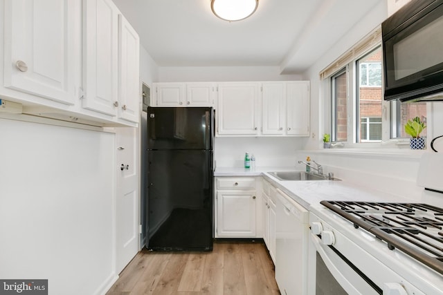 kitchen with light wood-style floors, light countertops, black appliances, and white cabinetry