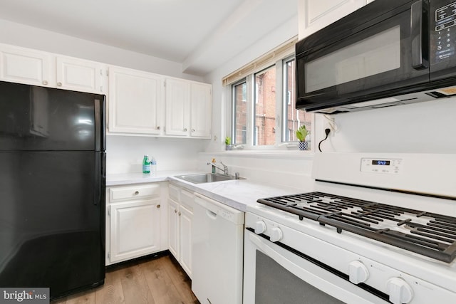 kitchen with a sink, black appliances, light countertops, and white cabinetry