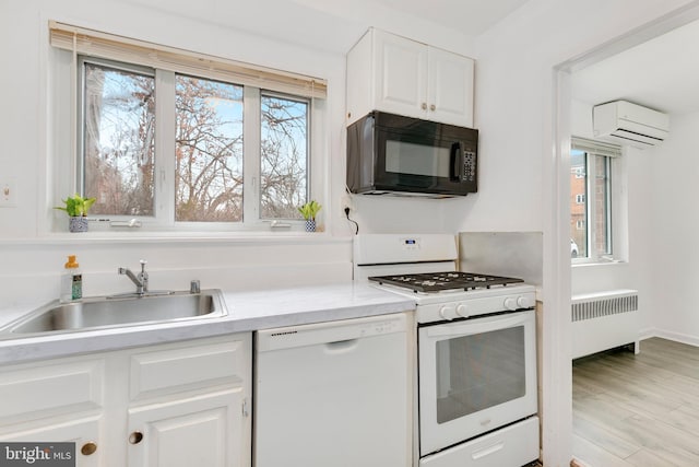 kitchen featuring white appliances, a sink, white cabinets, light countertops, and radiator heating unit