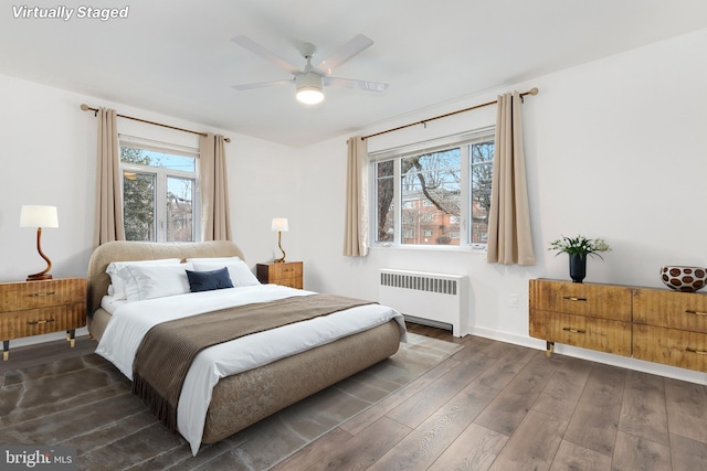 bedroom with baseboards, multiple windows, dark wood finished floors, and radiator