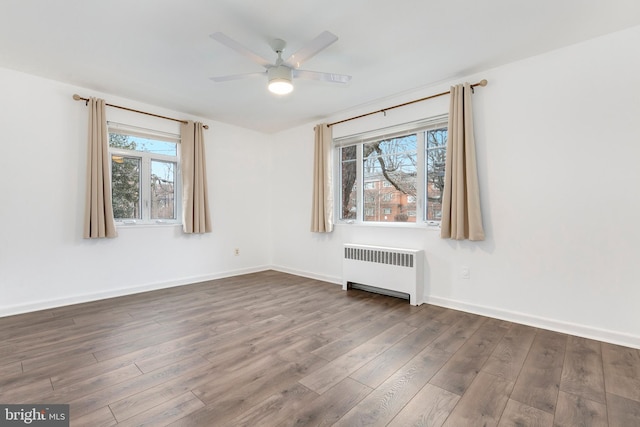 unfurnished room featuring radiator, dark wood-style floors, baseboards, and a healthy amount of sunlight