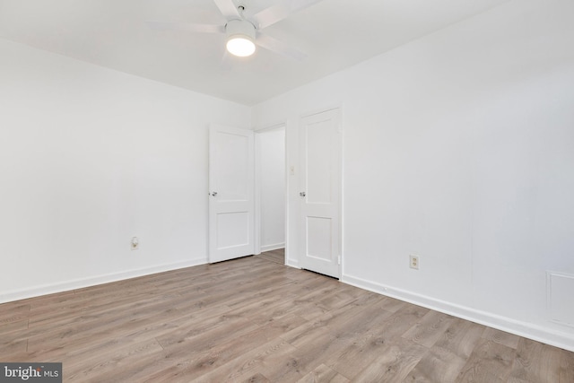 spare room with light wood-type flooring, a ceiling fan, and baseboards