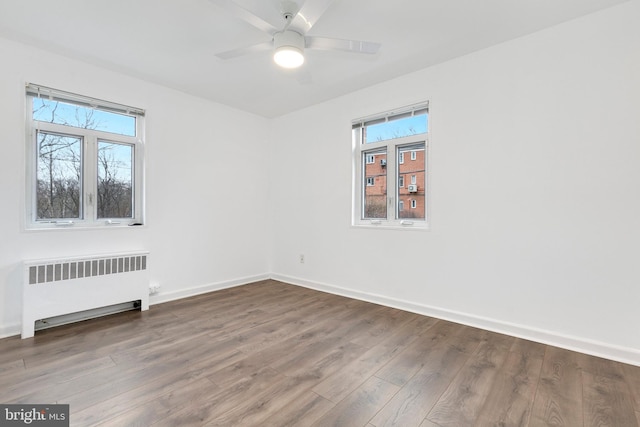 unfurnished room featuring radiator, ceiling fan, baseboards, and wood finished floors