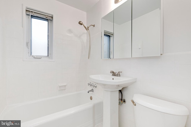 full bathroom with toilet, tile walls, and bathing tub / shower combination