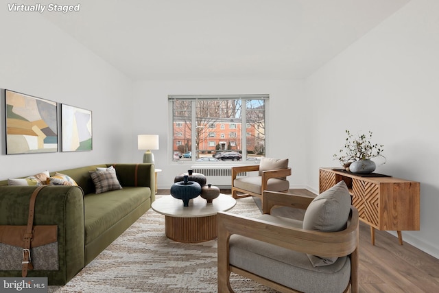 living area with radiator, baseboards, and wood finished floors