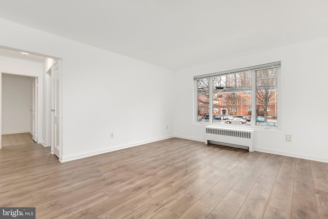 unfurnished room featuring light wood-style floors, radiator heating unit, and baseboards