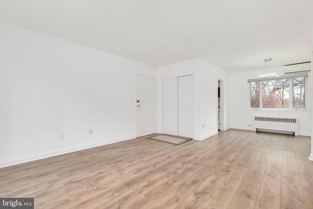 interior space featuring baseboards, light wood-type flooring, a wall mounted air conditioner, and radiator