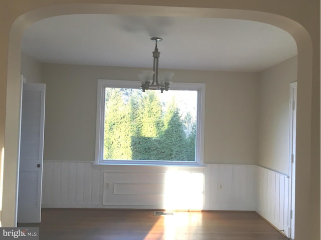 spare room featuring a chandelier, dark hardwood / wood-style floors, and plenty of natural light