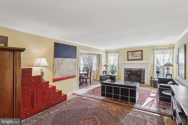 living area with baseboards, a brick fireplace, wood finished floors, and crown molding