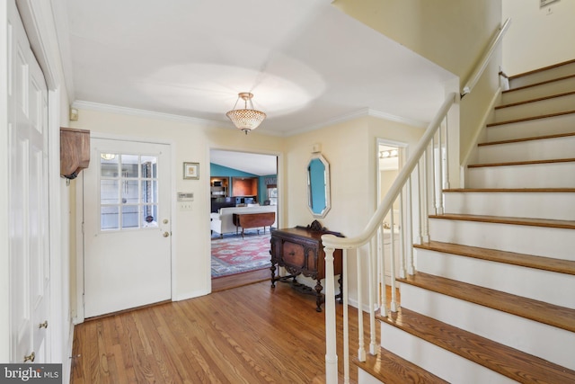 entryway with stairway, crown molding, light wood-style flooring, and baseboards