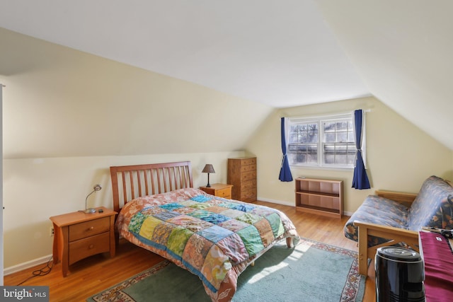 bedroom featuring baseboards, vaulted ceiling, and wood finished floors