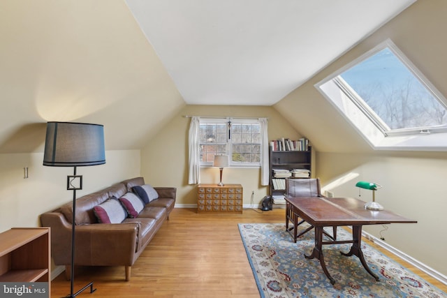 living area featuring lofted ceiling with skylight, baseboards, and wood finished floors