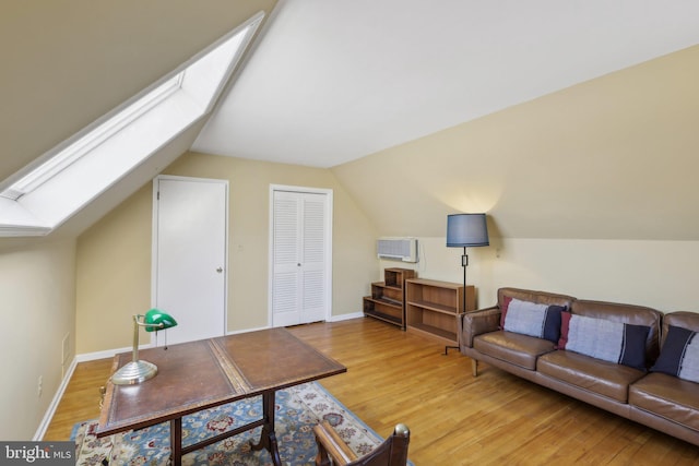 living room with light wood finished floors, lofted ceiling with skylight, visible vents, and baseboards