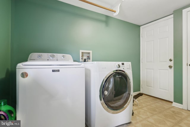 clothes washing area featuring light floors, laundry area, baseboards, and separate washer and dryer