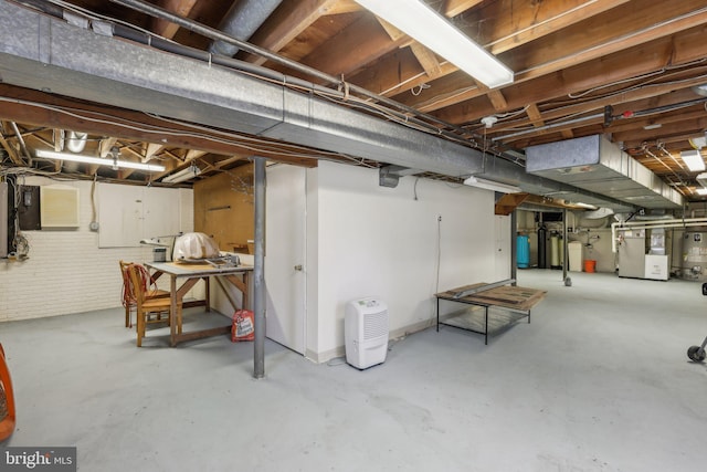 unfinished below grade area featuring heating unit, brick wall, and gas water heater