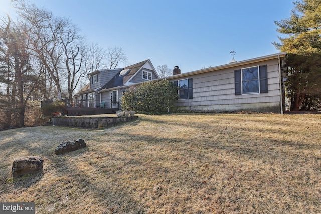 view of front facade featuring a chimney, a deck, and a front lawn