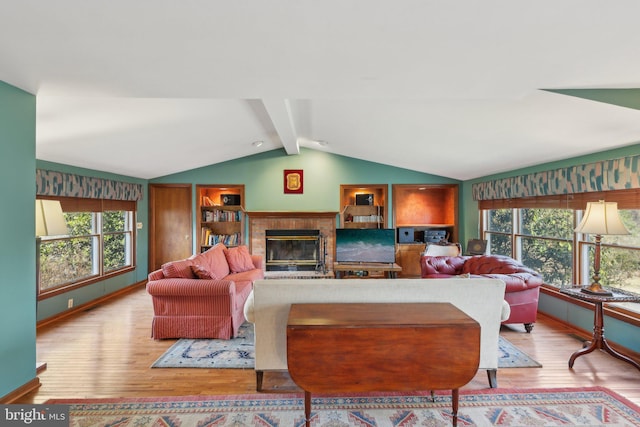 living room featuring vaulted ceiling with beams, a fireplace, a wealth of natural light, and wood finished floors