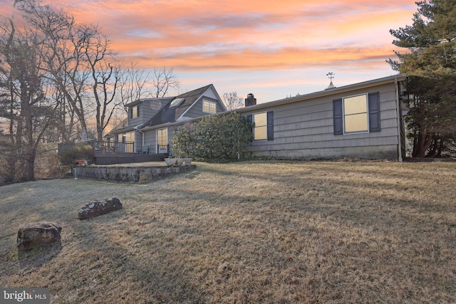 view of front of house with a deck, a chimney, and a front yard