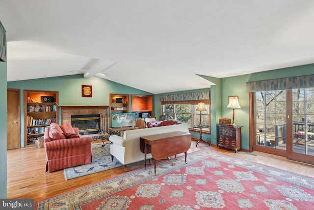 interior space featuring a brick fireplace, lofted ceiling with beams, and wood finished floors