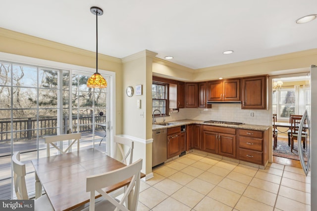 kitchen with tasteful backsplash, light stone counters, stainless steel appliances, crown molding, and a sink