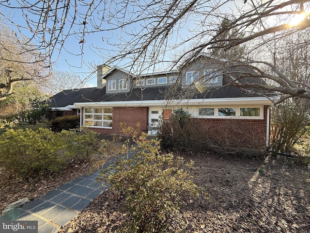 view of front of house with brick siding and a chimney