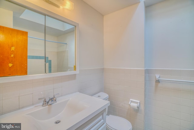 bathroom with tile walls, toilet, vanity, and walk in shower