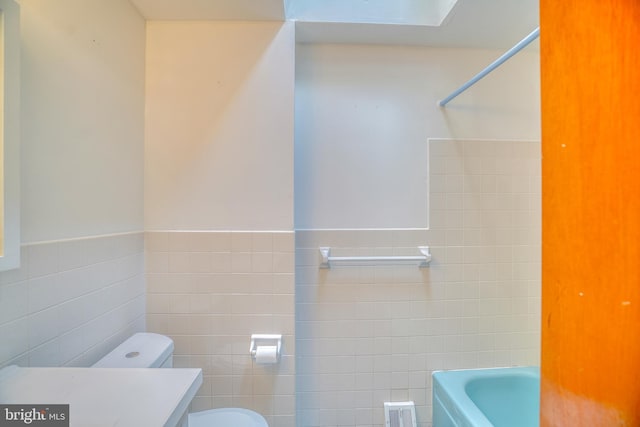 bathroom with tile walls, vanity, and toilet