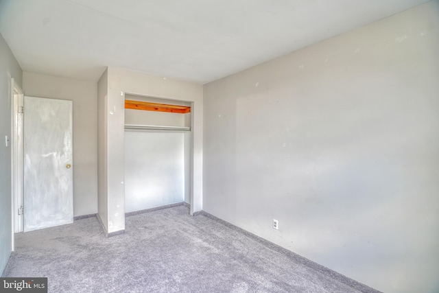 unfurnished bedroom featuring a closet and light colored carpet