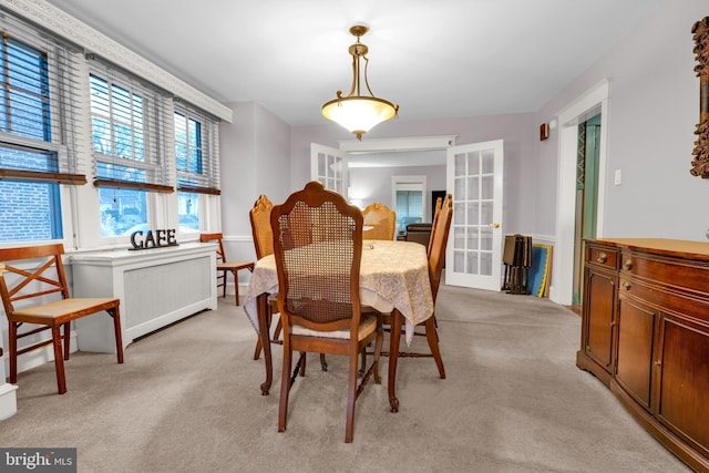 dining room with radiator, french doors, and light colored carpet