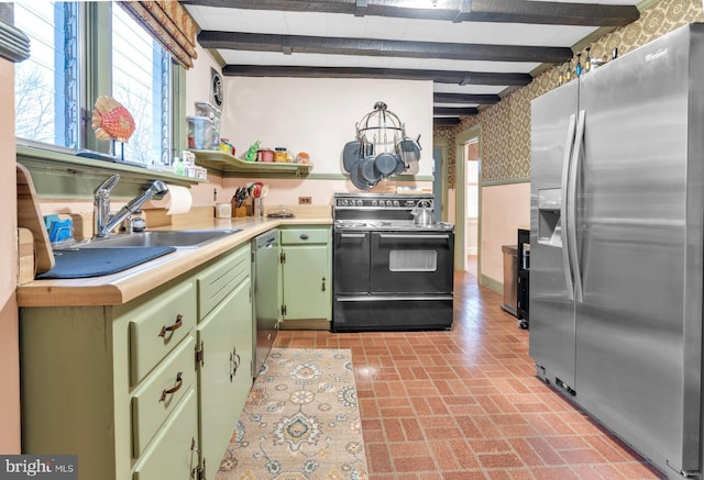 kitchen featuring wallpapered walls, appliances with stainless steel finishes, brick floor, light countertops, and green cabinetry