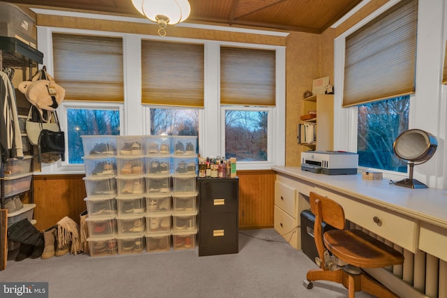 office space featuring wooden walls, built in desk, and light colored carpet