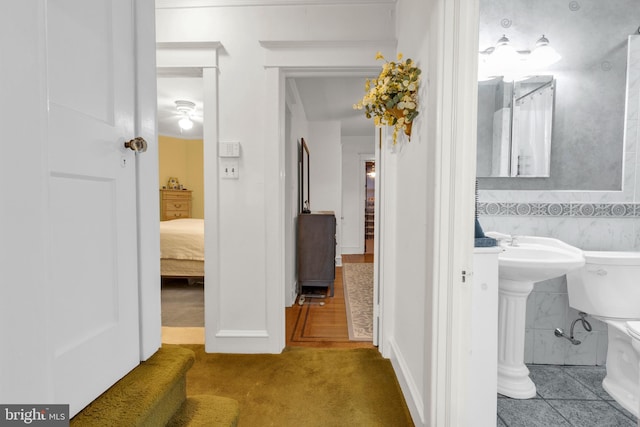 bathroom with tile walls, toilet, and tile patterned floors