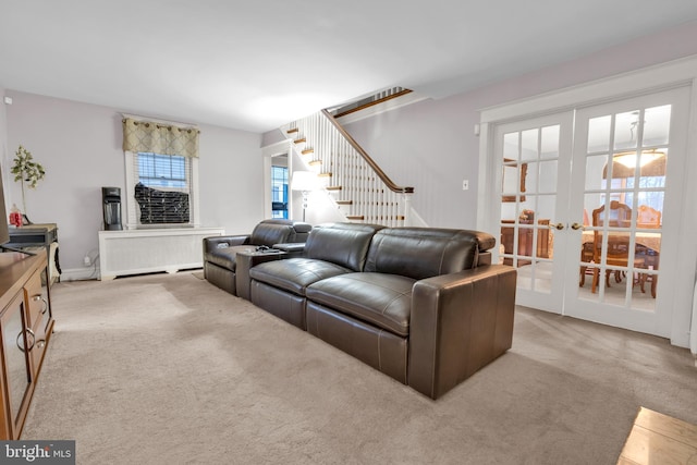 living room featuring light carpet, radiator heating unit, stairway, and french doors