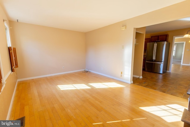 spare room with baseboards and light wood-style floors