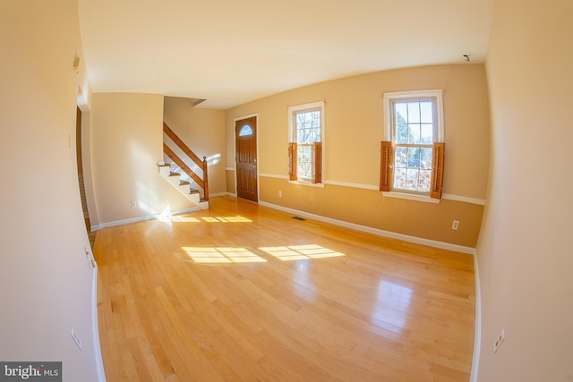 interior space with stairway, light wood-style flooring, visible vents, and baseboards