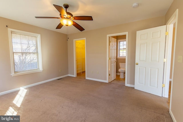 unfurnished bedroom with a walk in closet, ensuite bathroom, baseboards, and carpet floors