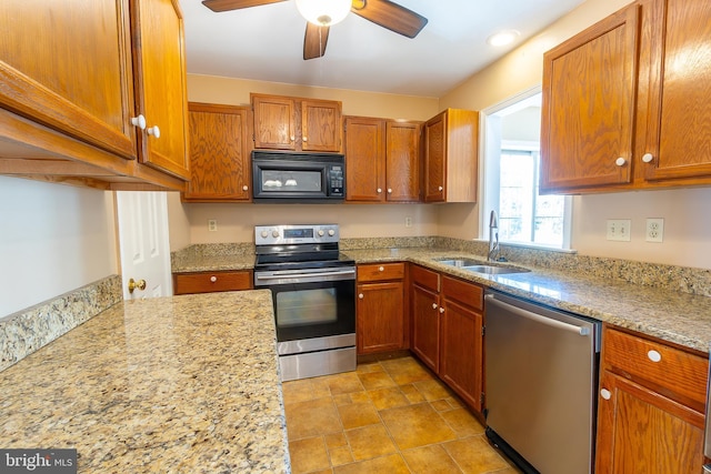 kitchen featuring brown cabinetry, stainless steel appliances, light stone counters, and a sink