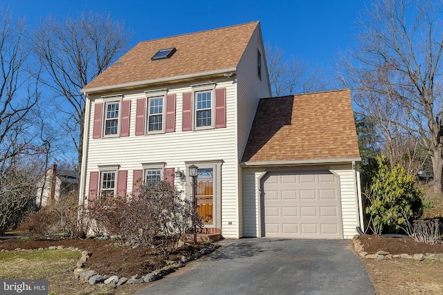 colonial house with aphalt driveway, a garage, and roof with shingles