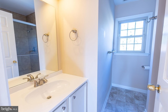 full bathroom with vanity, baseboards, and a tile shower