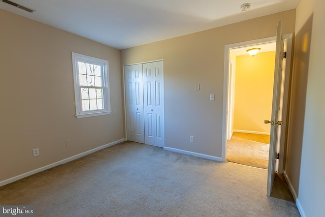 unfurnished bedroom with visible vents, baseboards, a closet, and carpet flooring