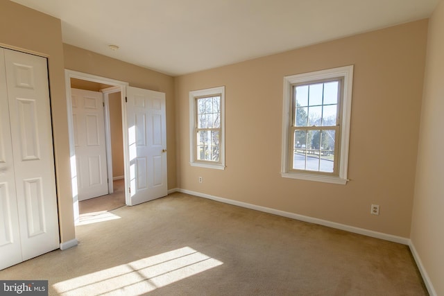 unfurnished bedroom featuring a closet, light colored carpet, and baseboards