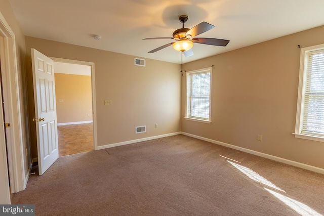 empty room with visible vents, carpet, and a healthy amount of sunlight