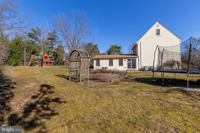 rear view of house featuring a yard, a playground, and a trampoline