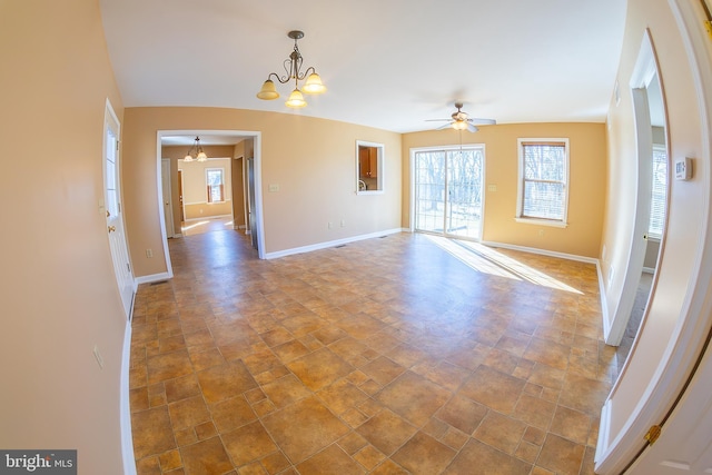 spare room with stone finish floor, ceiling fan with notable chandelier, and baseboards